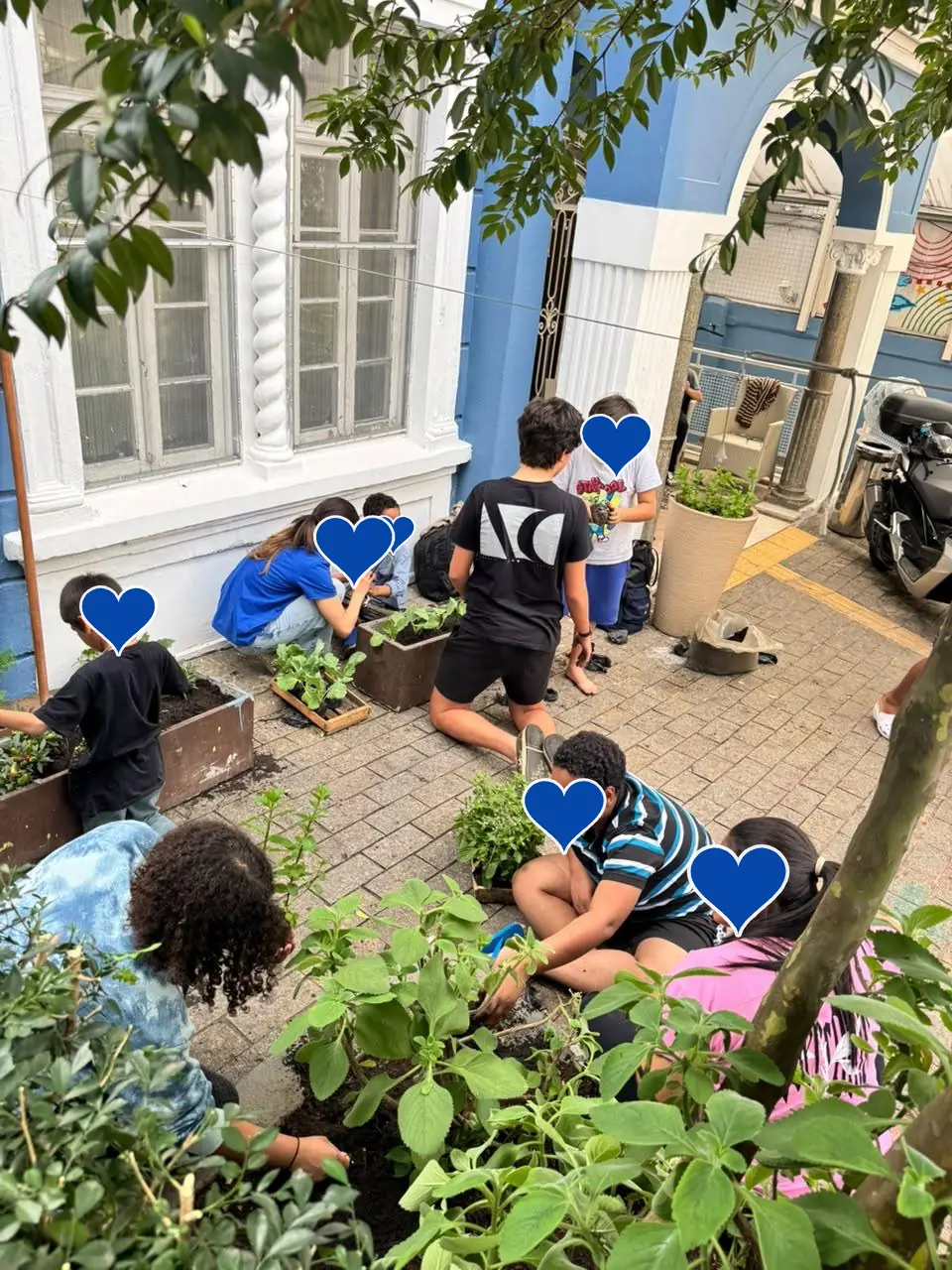 Crianças e voluntários plantando mudas em canteiros de madeira